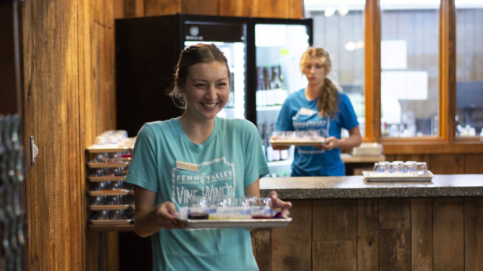 A Fenn Valley staff member carries a tray of tasting pours out to a group.